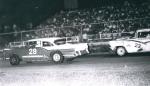 Early Model action in March 1966 at Gold Coast Speedway plays to an SRO crowd as Lou Haines leads Portus Mellette...