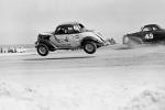 Red Farmer catches some air during the 1953 Modified race as Ralph Moody #49 works the high side....
